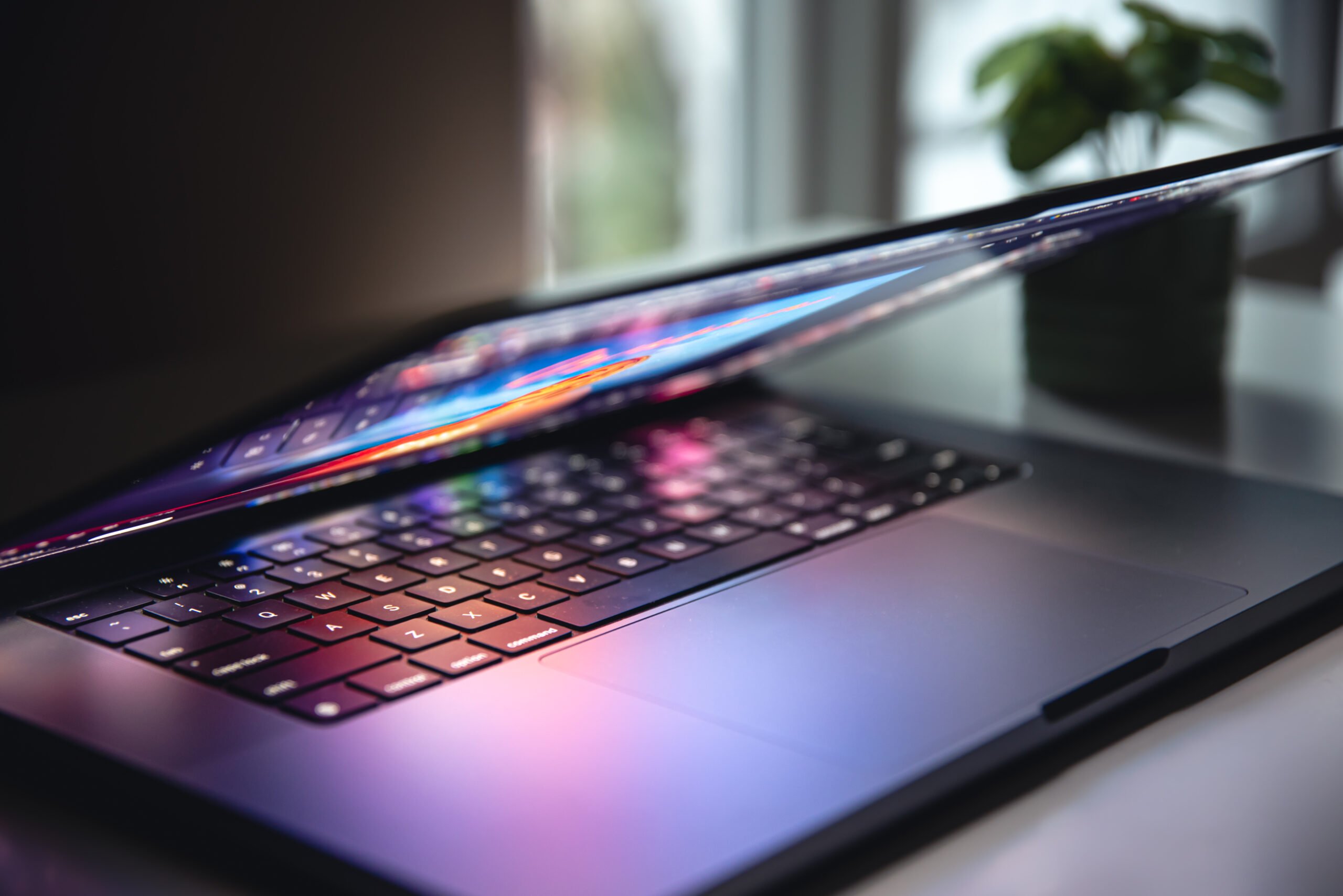 Colorful close up of a laptop keyboard working home or office at night with the illumination of a screen display with multiple colors background..
